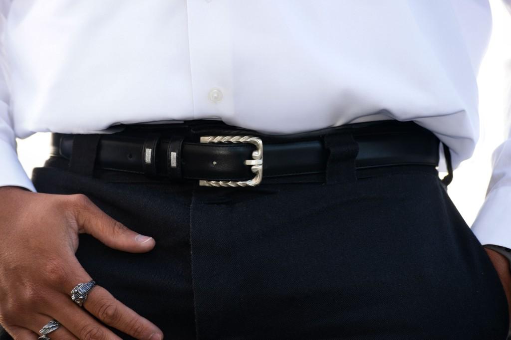 Silver rope edge belt buckle on black leather with hand worn stack rings, styled for scale.