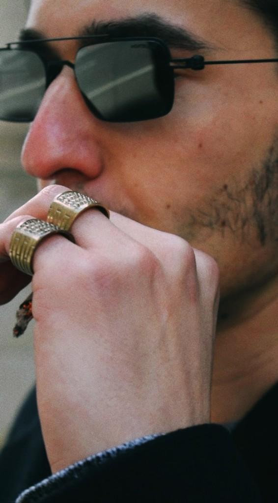 Hand wearing wide textured brass band rings, lifestyle portrait.